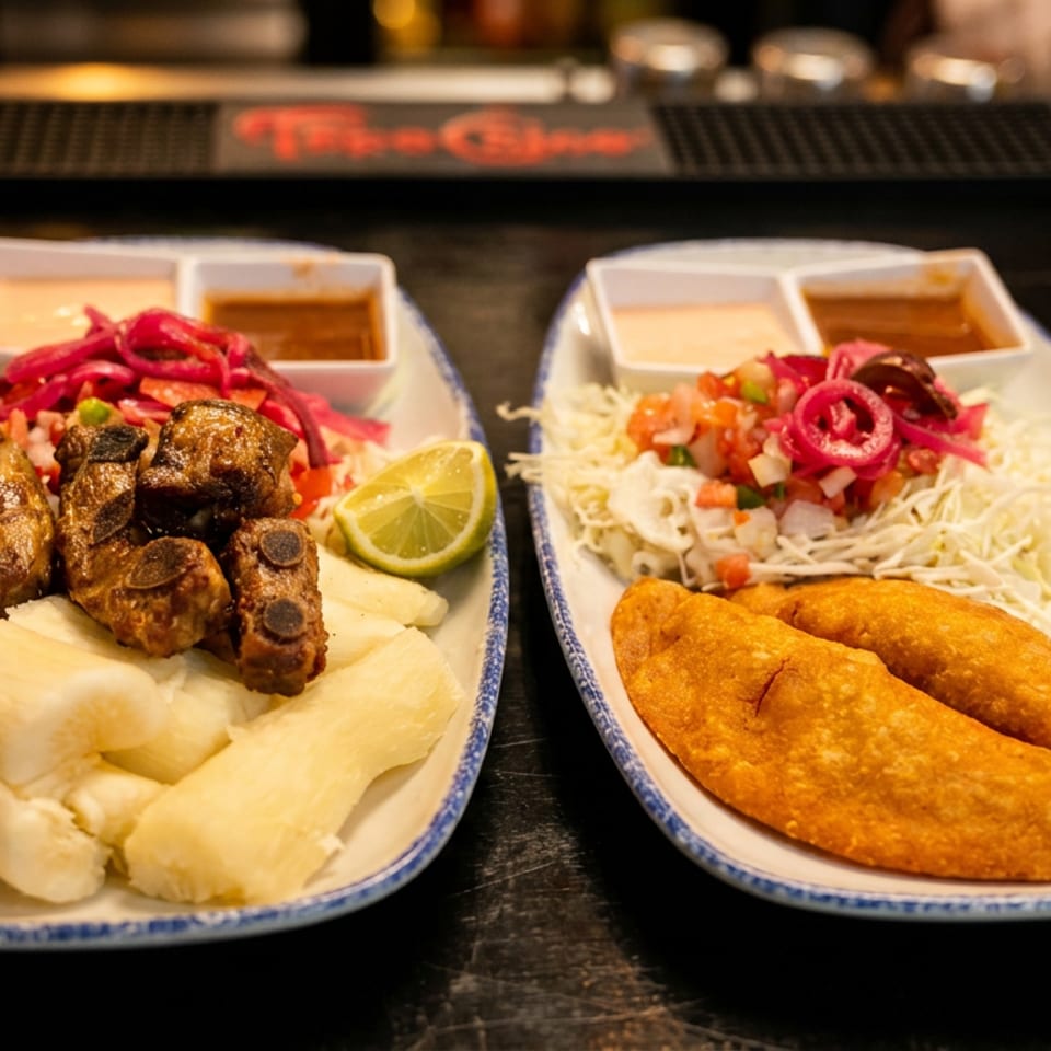 Delicious plates of ribs with yuca and empanadas with salad, garnished with lime and pickled onions.